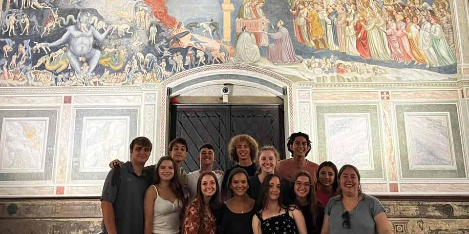 A group of students in front of a mural in Italy.